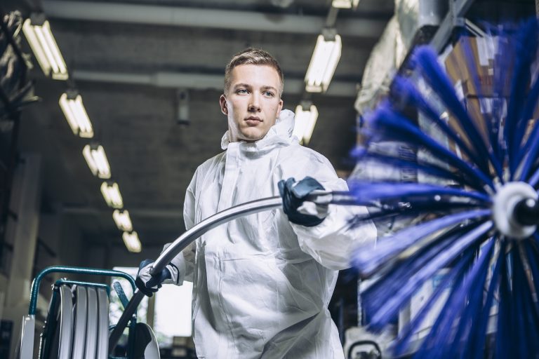 een man in een wit pak die een borstelmachine bedient