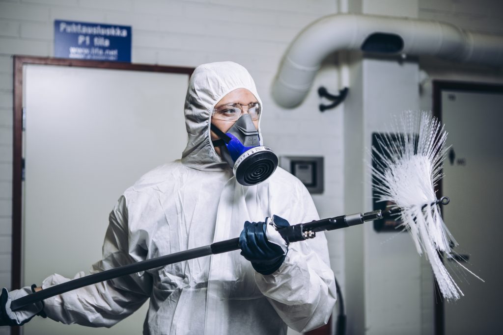 een man in een wit pak die die borstelmachine in zijn handen heeft.