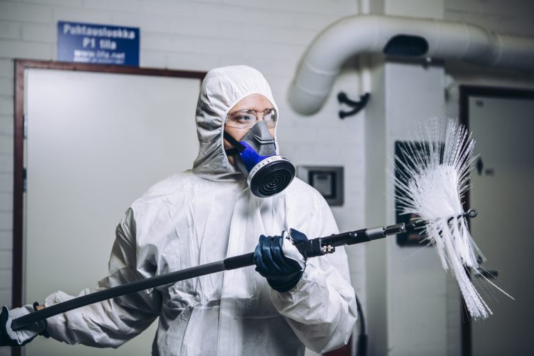 een man in een wit pak die die borstelmachine in zijn handen heeft.