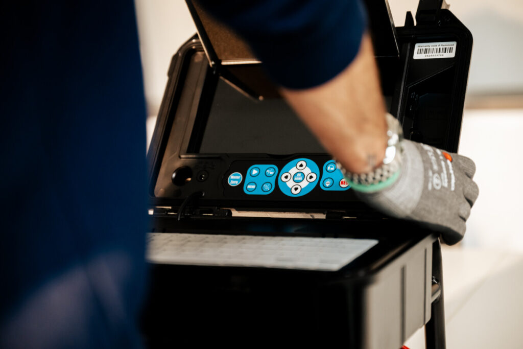 een man met werkhandschoenen aan die een camduct inspectiecamera vastneemt